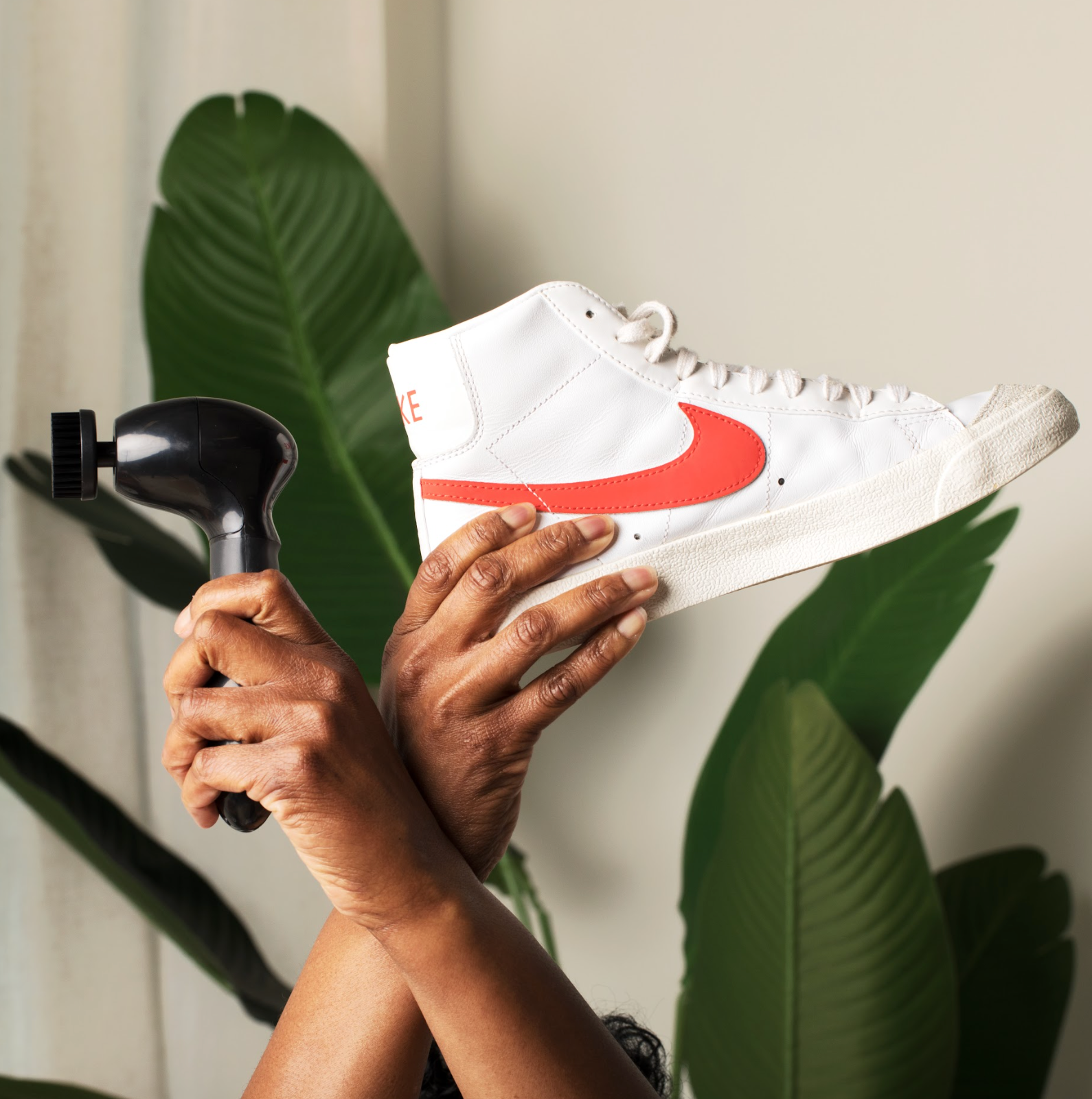 Arms holding up Kean Kicks scrub brush with a clean white Nike sneaker